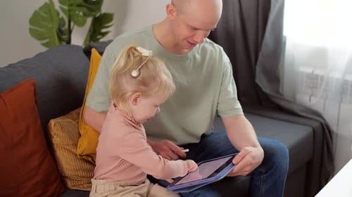 A Child with Cochlear Implants Plays with a Tablet Computer with His Father