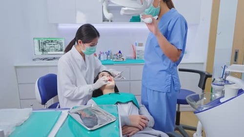 Asian female dentist wear face mask checking or examining tooth for patient girl in dental clinic.