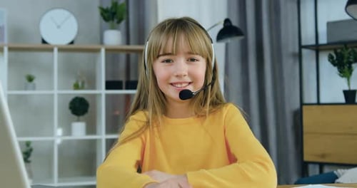 Chica con auriculares vestida con ropa casual sentada frente a la cámara en el fondo