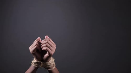 Hand Tied with Rope Against Black Background