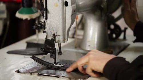 Un vieux maître fait des points de suture à l'aide d'une machine à coudre industrielle vintage sur une ceinture
