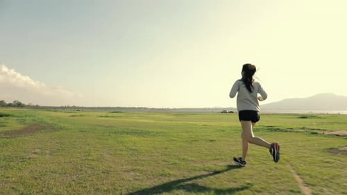 Woman Running Outdoors in Green Field