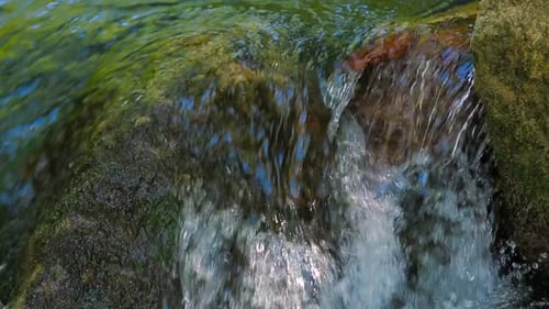 Waterfall Cascading Over Mossy Rocks on a Sunny Day