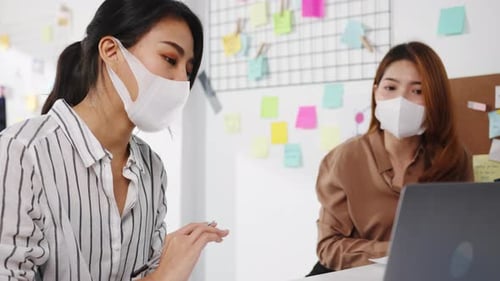 Businesspeople using computer presentation meeting and wear face mask back in office