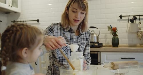 Young Mother and Daughter Having Fun Baking Cookies in the Kitchen Together