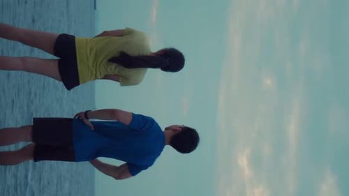 Couple Stretching on Beach at Sunrise