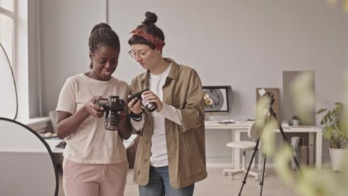 Two Cheerful Women Posing with Cameras in Studio