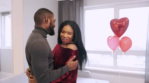 Affectionate Couple Embracing Near Heart Balloons Indoors
