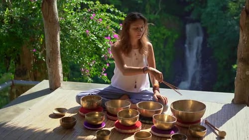 Woman Meditating with Singing Bowls in Nature