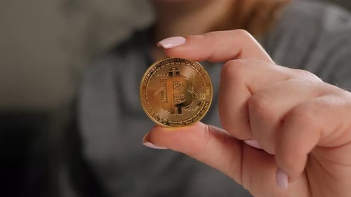 Woman Holding Golden Bitcoin in Fingers Close Up