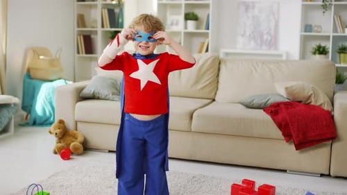 Energetic Boy in Superhero Costume Poses at Home