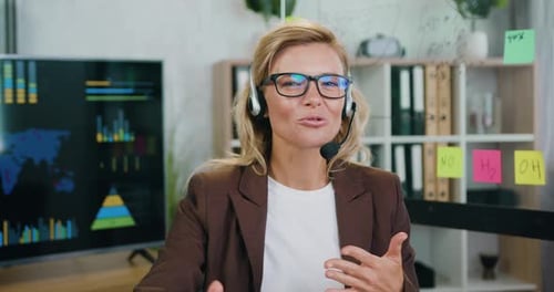 trabajadora de un centro de llamadas con auriculares de teléfono y algo hablando por la cámara en línea