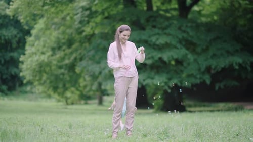 Family Having Fun. Mom And Child Making Soap Bubbles Outdoors