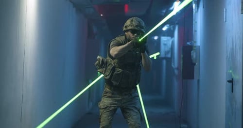 Soldier Aims Firearm with Green Laser in Dark Hallway