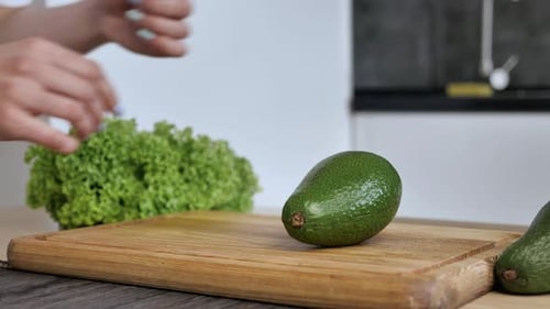 Woman Cutting Fresh Avocado in Kitchen