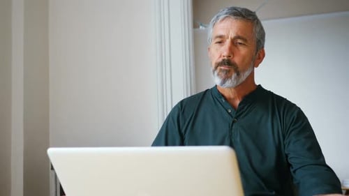 Man Eating a Sandwich While Using Laptop