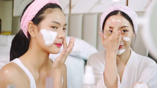 Two Young Women Apply Face Cream at Home