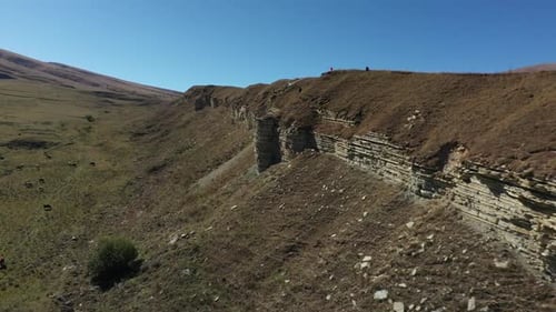 Hikers on Rocky Ridge in Grassy Mountain Landscape