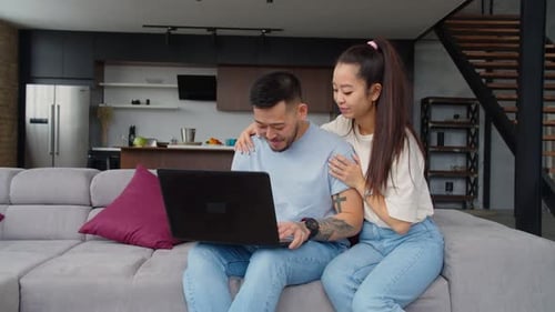 Couple Using Laptop Computer Together on Sofa At Home