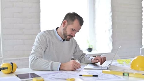 Young Architect with Laptop Doing Paperwork in Office