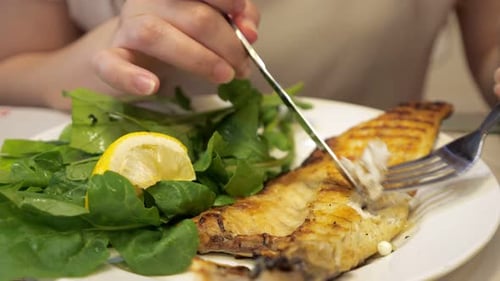 Mann isst Bratfisch mit Gabel und Messer im Restaurant, Gericht Nahaufnahme.