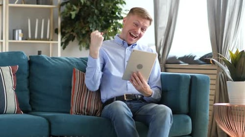 Happy Man Celebrating Success With Tablet at Home