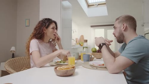 Couple Eating Breakfast and Talking in Bright Kitchen