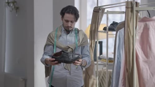 Young Adult Man Examines Black Leather Shoe