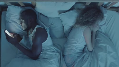 Man Using Phone while Girlfriend Sleeping