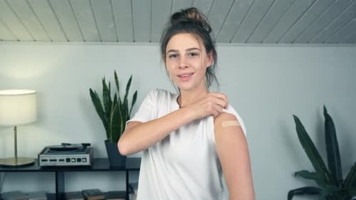 Woman Points to Bandage After Vaccination