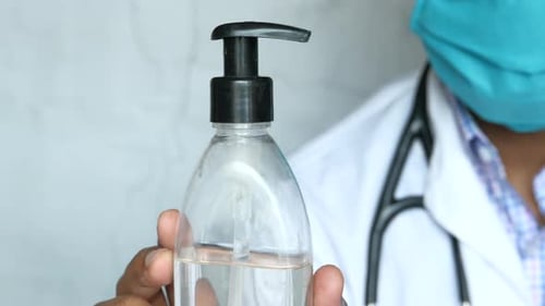 Doctor in Face Mask Holding Hand Sanitizer Gel, Close Up