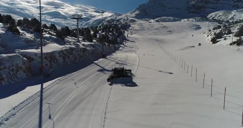 Snow Groomer Preparing Ski Slope in Snowy Mountains