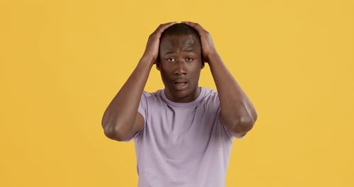 Emotionaler Afroamerikaner, der panisch seinen Kopf berührt