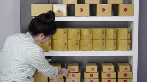 young woman entrepreneur counting parcel boxes in her own job shopping online business at home