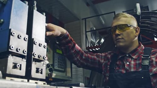 Industrielle Produktion Ein junger Arbeiter schweißt Gürtelstaubfunken, die vor dem Hintergrund seines