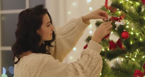 Woman Decorating Christmas Tree in Cozy Home