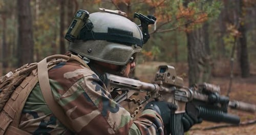 Soldier in Camouflage with Rifle in Woodland Area