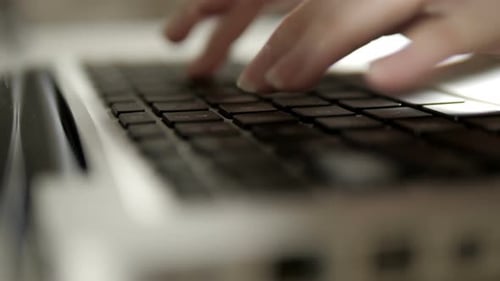 Close-up of hands typing on laptop keyboard