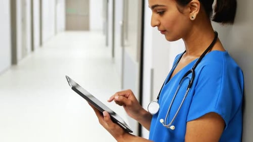 Healthcare Worker Using Tablet in Hospital Hallway