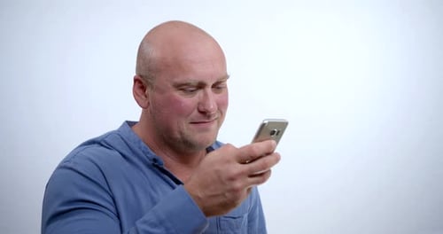 Bald Man Looking at Cellphone Indoors Smiling