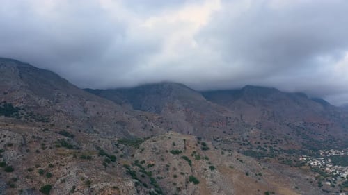 Flying above stony edges at deserted mountains. Clouds covered Mountain.