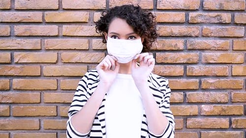 Brunette woman shows step by step how to put on mask to avoid contamination by SARS-CoV-2 coronaviru