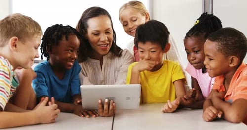Teacher Teaching School Kids On Digital Tablet In Classroom