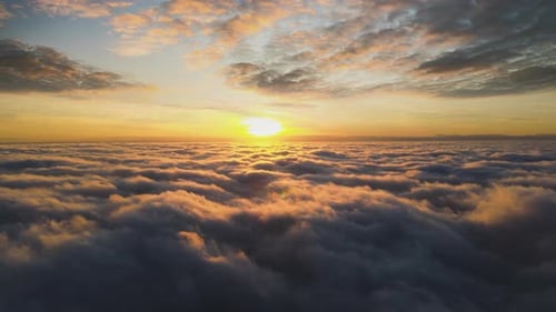 Time lapse footage of aerial view of vibrant yellow sunrise over white dense clouds with blue sky