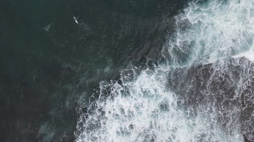 Top down aerial view of giant ocean waves crashing and foaming