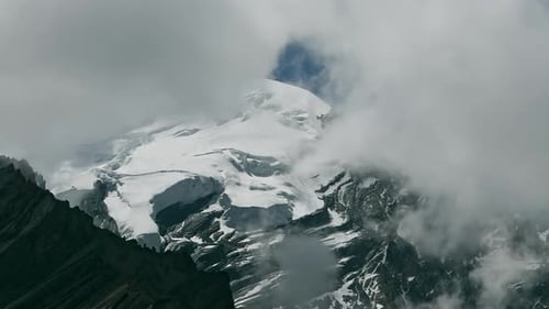 Timelapse Clouds Swirl Over a Mountain Valley a Snowy Peak in the Distance