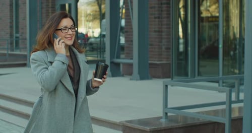 Woman in the Glasses Goes Near Business Center with Documents and Talks on the Phone