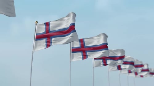 Multiple Waving Flags on Flagpoles Against Blue Sky