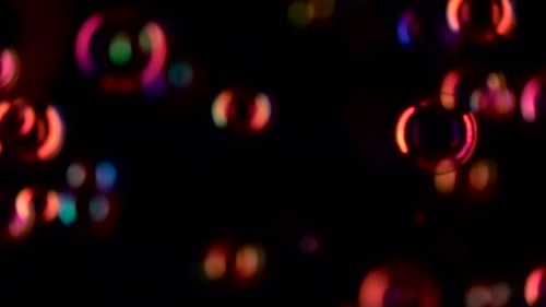 Red Soap Bubbles Fly in the Air Close Up. Slow Motion. Black Background