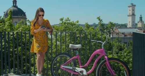 Beautiful Pretty Teenager Girl Riding a Bicycle and Using Her Mobile Phone Smartphone To Communicate